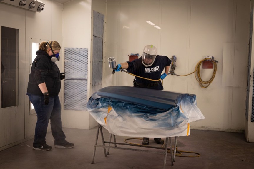 Danica Wooster working with MCST student Andrew Zuidema refinishing a hood in the paint booth (Photo credit: Zoe Richardson, a student in MCST Design Technology program).