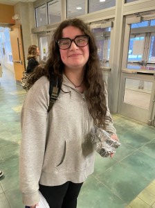 A student smiles at the camera while holding baked goods they made during an Extended Day Enrichment program. 