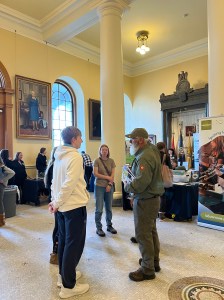 In a crowded room, a group of teenagers speak to two uniformed Maine Game Wardens.