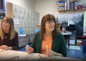 Commissioner Maiken and Chief Innovation Officer Page Nichols sit at a school table working on their BARR U-Time activity. 