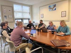 Mt. Blue's Community Connect meeting is where educators and school community members meet to discuss at-risk students. Mt. Blue educators and school community members sit around a conference table talking about BARR with laptops in front of them.