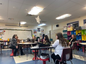 Six educators sit in a classroom facing the front of the class. They are BARR teachers holding a Block Meeting. 