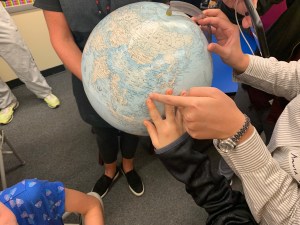hands pointing on a globe