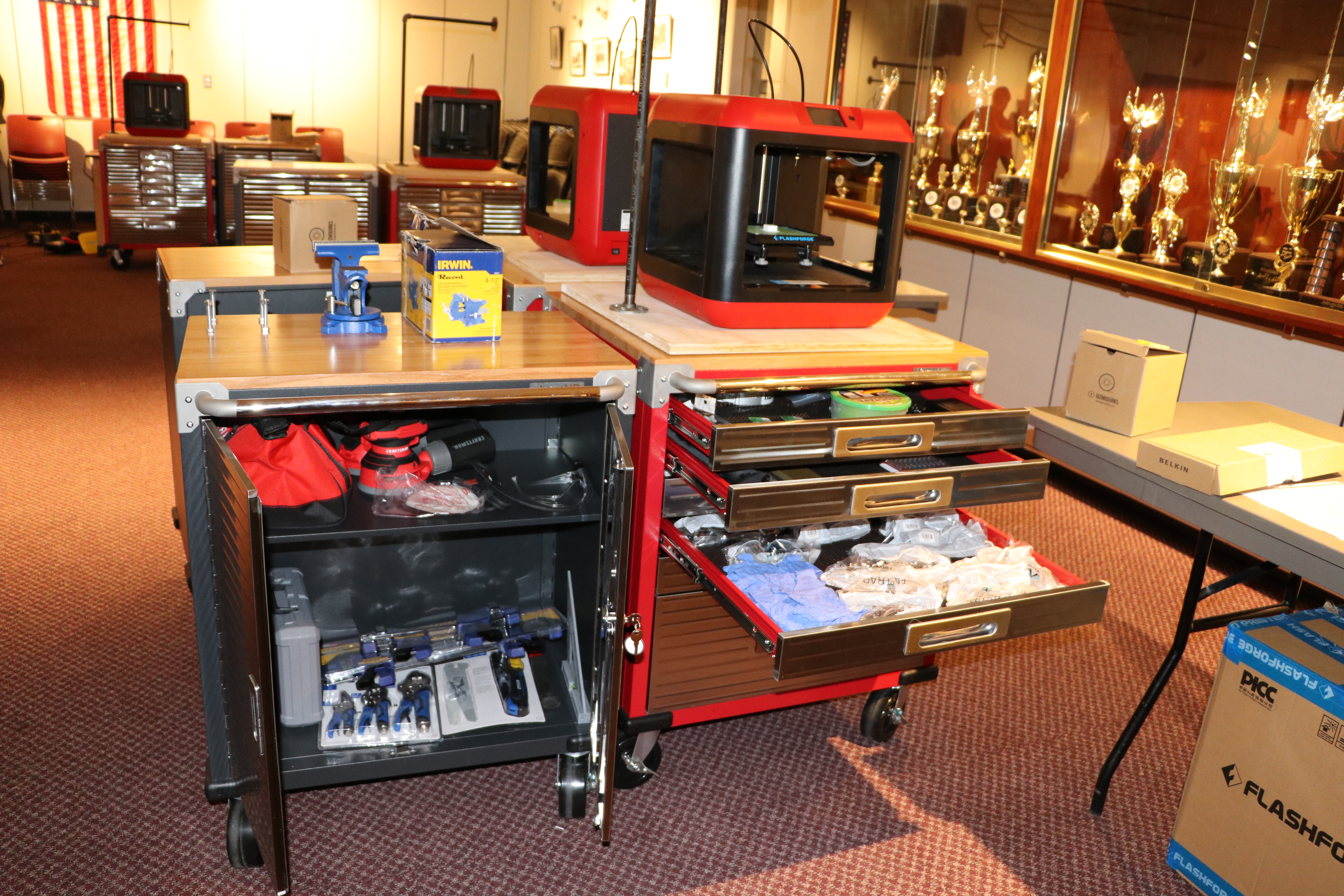 The STEAMRoller Cart includes: Seville Classics UltraHD 2-Door Rolling Cabinet and a 6-drawer Rolling Storage Cabinet, Vise, Portable Vise Table, Power Strips, Cordless Orbital Hand Sander, Corded Orbital Hand Sander, Power Drill, Impact Power Drill, Rotary Dremel Tool, Irwin Clamps, Kobalt 100-Piece Household Tool Set with Hard Case, Hand Tool Bag, Hammer, Locking Pliers, Tape Measure, Speed Square, Spade Bits, Flash Forge 3D Printer, 3D Printer Tool Set, Frog Tape, Duct Tape, Rocketbook, FriXion Pens, iPod Touch & Case, Tripod, Raspberry Pi, Soldering Iron, Scrappy Circuits, Safety Goggles, Disposable Gloves, Breakout of the Box DRAWER, and a Breakout EDU Kit.