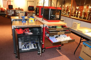 The STEAMRoller Cart includes: Seville Classics UltraHD 2-Door Rolling Cabinet and a 6-drawer Rolling Storage Cabinet, Vise, Portable Vise Table, Power Strips, Cordless Orbital Hand Sander, Corded Orbital Hand Sander, Power Drill, Impact Power Drill, Rotary Dremel Tool, Irwin Clamps, Kobalt 100-Piece Household Tool Set with Hard Case, Hand Tool Bag, Hammer, Locking Pliers, Tape Measure, Speed Square, Spade Bits, Flash Forge 3D Printer, 3D Printer Tool Set, Frog Tape, Duct Tape, Rocketbook, FriXion Pens, iPod Touch & Case, Tripod, Raspberry Pi, Soldering Iron, Scrappy Circuits, Safety Goggles, Disposable Gloves, Breakout of the Box DRAWER, and a Breakout EDU Kit.