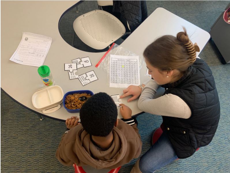 CBHS senior, Molly Neuner, working with a student in a 1st and 2nd grade ESOL classroom as part of her participant observation during the intensiv