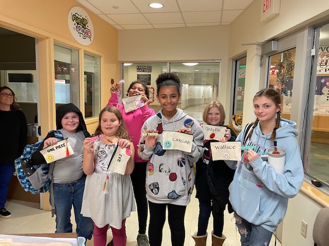 Five Ridge View Community School Students hold up their screen printing projects they created in the Extended-Day Enrichment program while smiling.