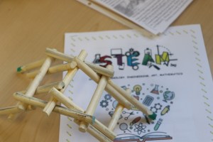 stick bridge with paper underneath that says, "STEAM"