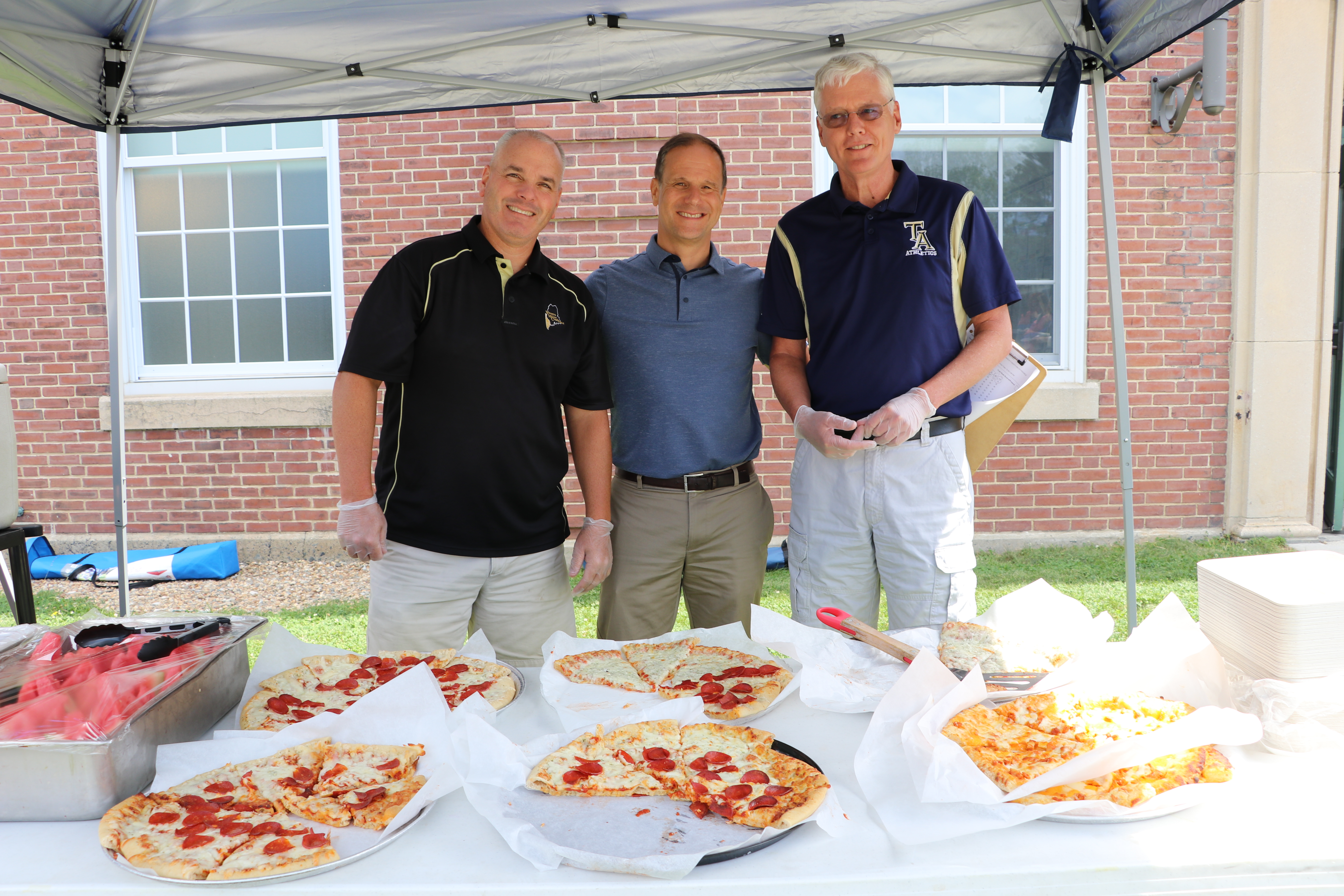 Traip Academy Assistant Principal/Athletic Director, Kittery School Department Superintendent, Eric Waddell, and Michael Roberge, Traip Academy Principal John Drisko serving pizza at the event