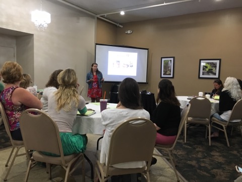 room of educators sitting at tables listening to speaker