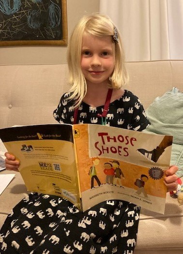 photo of J. McQuilken, second grade student at Captain Albert W. Stevens School in Belfast, with a copy of the book Those Shoes by Maribeth Boelts.