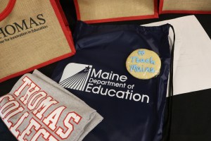 t-shirt, backpack and cookie with Thomas college and Maine DOE logos.
