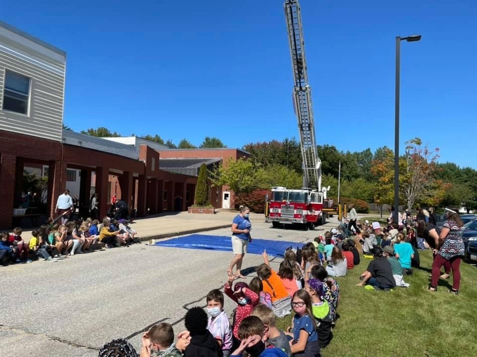Fire truck with latter up. students gathered outdoors watching