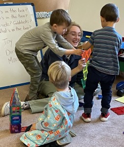 Educational Technician, Natalie Kunzinger, joins children in the block area where they are using magnetic blocks to build houses.