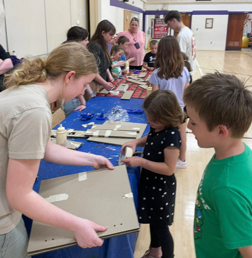 In May, the Bucksport High School Robotics Team—or FIRST Robotics Competition (FRC) Team 6329—and their incredible robot, Tide, once again proved they’re among the best in the world. The Bucksport High School Robotics Team had a phenomenal season, racking up an impressive 55-11 record. The team clinched victories at both the Pine Tree and Southern Maine events, earned a runner-up title at the prestigious New England Championships, and finished eighth in the highly competitive Curie Division at the World Championships—solidifying a place among the global elite. Fresh off of an outstanding season, the students of FRC Team 6329 were eager to give back to the community that had supported them. They saw an opportunity to share their passion for STEM (Science, Technology, Engineering, and Mathematics) and robotics with younger students and seized it. This spring, the team launched a new after-school program at the Downeast Family YMCA, bringing together innovation, creativity, and community engagement. Designed for elementary-aged students, this program introduced engineering and robotics fundamentals to kids by having them build functional robots entirely out of cardboard. These weren’t just any cardboard creations, though. Thanks to a new laser cutter purchased through a Maine Department of Education (DOE) Maine Learning Technology Initiative (MLTI) “Teach with Tech” grant, the team was able to design and cut precise parts for robots. Bucksport students Madi Robinson and Izzy McSharry, with support from their teachers, designed the robots in their high school engineering classes and fabricated all of the components used by these younger students. "Cardboard might sound low-tech, but it’s actually a fantastic material for rapid prototyping,” a team member said. “It’s safe, inexpensive, and with the laser cutter, we can create detailed and functional components.” The laser cutter, acquired earlier in the 2024-2025 school year through the MLTI grant, has expanded the Bucksport High School Robotics Team’s capabilities—not only for its competitive work but also for its outreach. This YMCA after-school program grew from a desire to spark early interest in STEM and give back to the local community. Supported by their robotics coaches, students developed hands-on activities that taught basic engineering principles, teamwork, and creative problem-solving. “Our students really took the lead,” FRC Team 6329 coach John Boynton said. “They weren’t just mentoring; they were designing, teaching, troubleshooting, and encouraging kids to believe they could be engineers, too.” Sophomore FRC Team 6329 member Lily Frost designed this pilot program, and the team hopes it is just the beginning. This summer, the team is running a one-day-per-week program for more than 50 kids through the YMCA day camps in Bucksport. Future plans may also include modules on 3D printing, Computer-Aided Design (CAD), and laser cutter training. This young, passionate team from Bucksport High School is proving that small-town schools can lead big ideas—and that the future of engineering is already in capable hands. This story was submitted by Bucksport High School. To submit a good news story to the Maine DOE, please fill out the good news submission form.