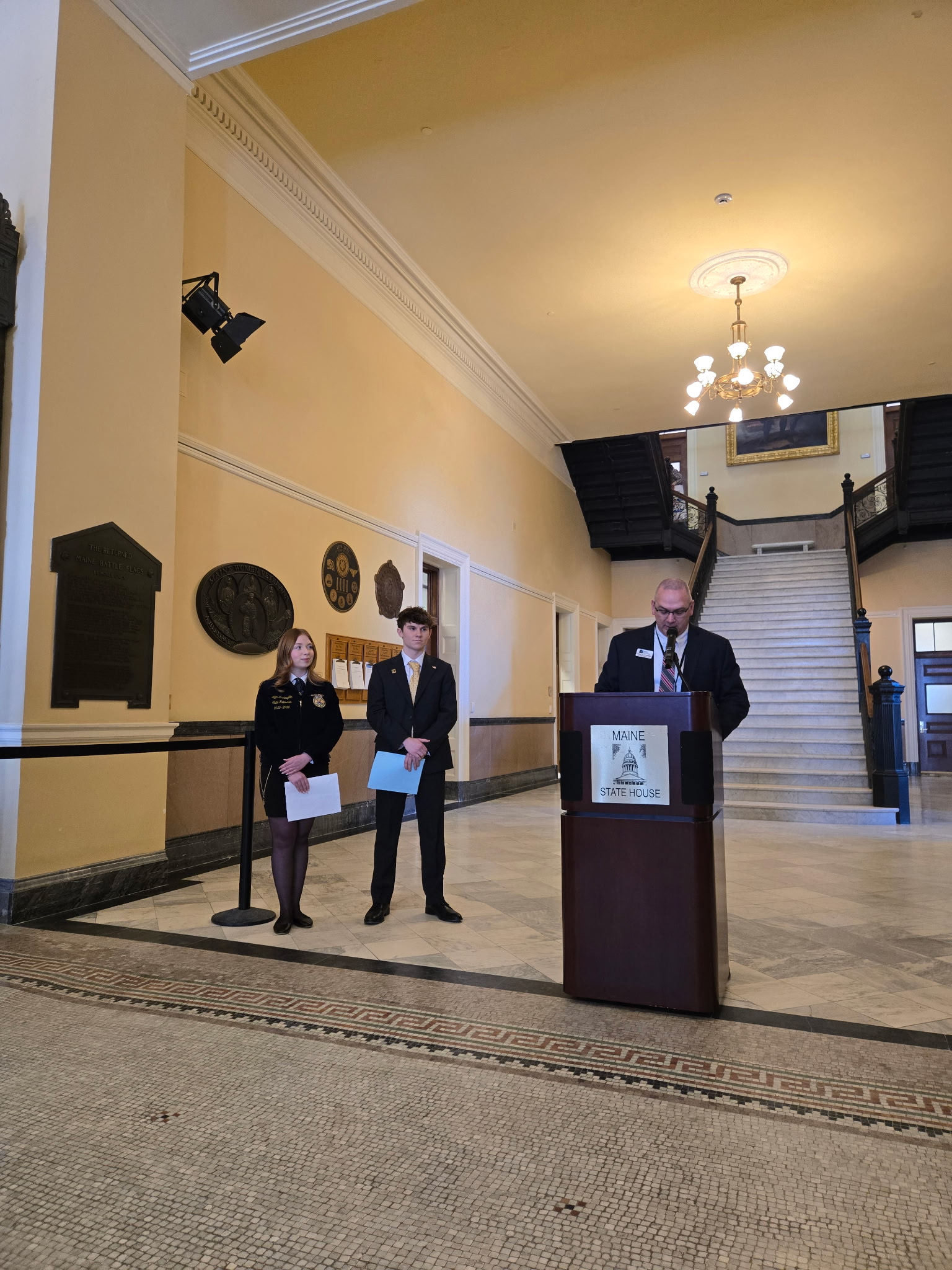 Speakers from day two of the events: Sanford Regional Technical Center Director Matt Petermann (at the podium), FFA State Reporter and SMCC Student Jillian McLaughlin (far-left), and Westbrook Regional Vocational Center student Jackson Lavertu (middle).