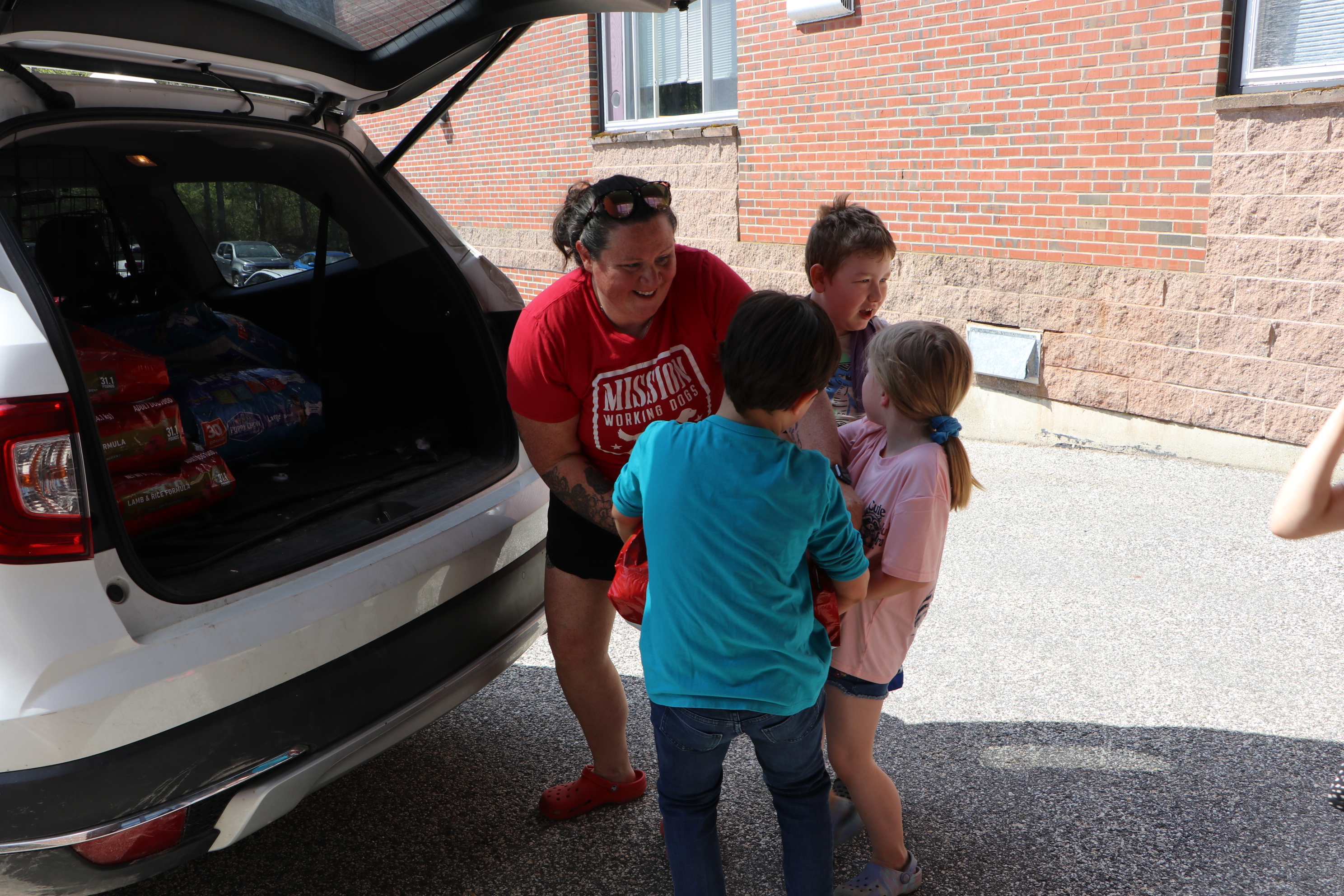 Dog handler Lauren King helps students load bags of dog food into a vehicle.